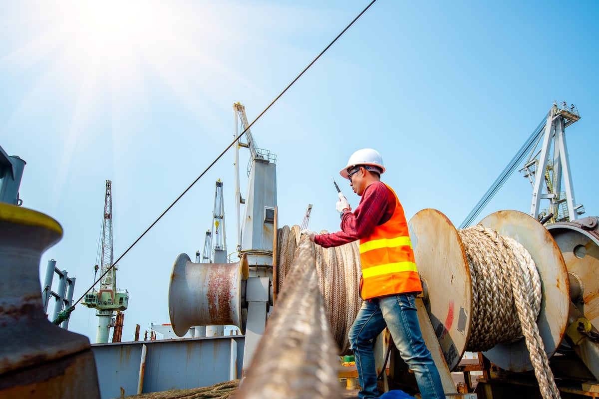Workers on a vessel deck handling ropes and winch gear