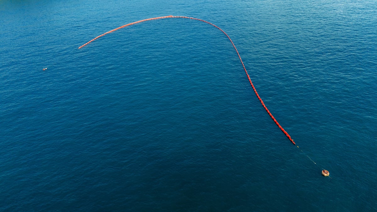 Long containment boom deployed in a curve across open water
